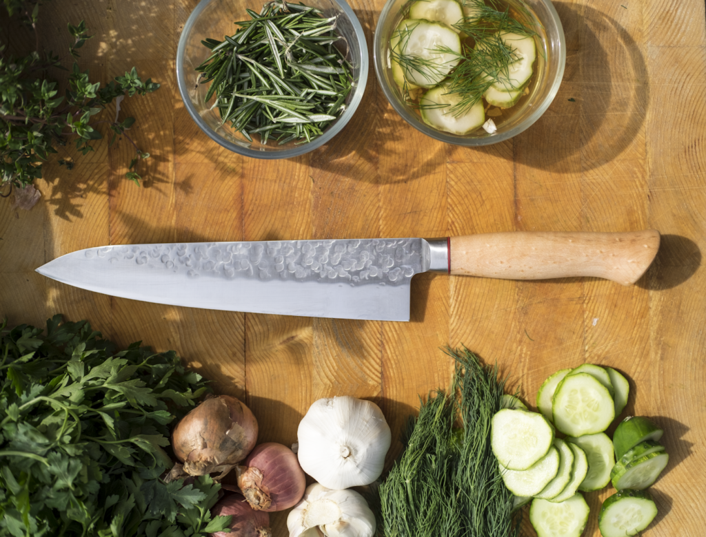 Knife surrounded by vegetables and herbs